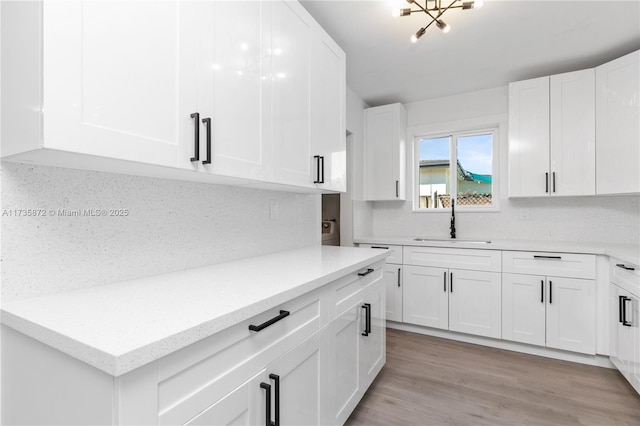 kitchen with white cabinetry, light hardwood / wood-style floors, sink, and tasteful backsplash