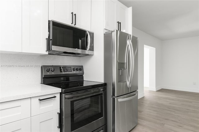 kitchen with backsplash, appliances with stainless steel finishes, light wood-type flooring, and white cabinets