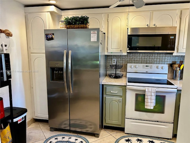 kitchen with appliances with stainless steel finishes, light tile patterned floors, white cabinets, and decorative backsplash