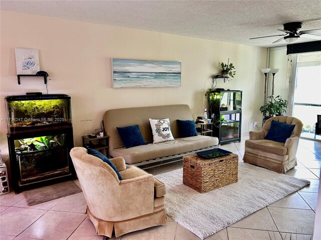 living room with tile patterned flooring, ceiling fan, and a textured ceiling