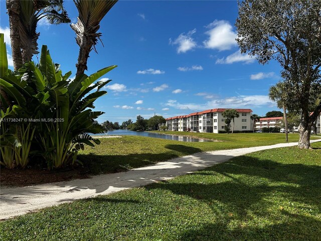 view of home's community with a water view and a lawn