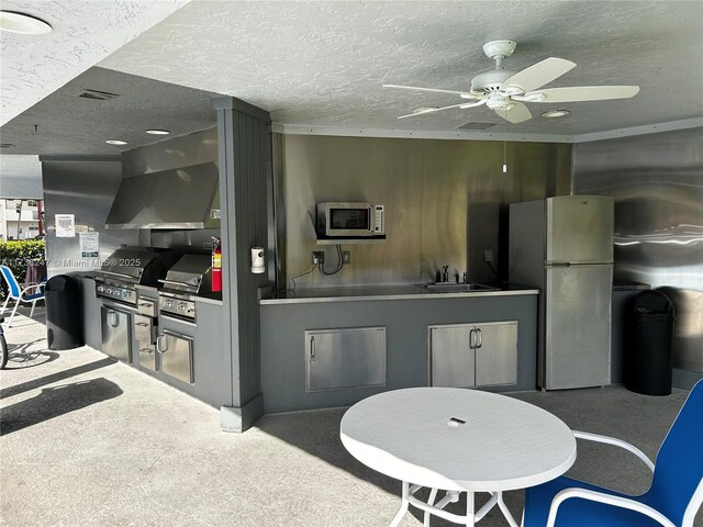 kitchen featuring sink, ventilation hood, refrigerator, a textured ceiling, and carpet flooring