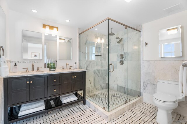 bathroom with a shower with shower door, tile walls, vanity, toilet, and tile patterned floors