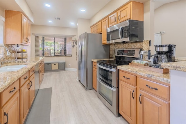 kitchen with light brown cabinetry, sink, backsplash, stainless steel appliances, and light stone countertops