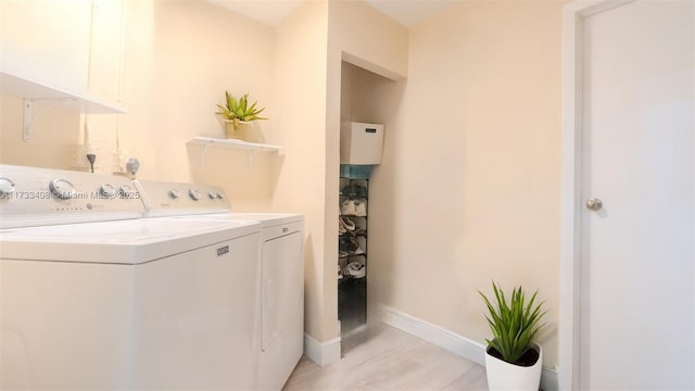 clothes washing area with washing machine and clothes dryer and light hardwood / wood-style flooring