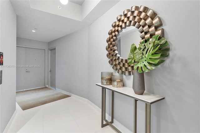 hall featuring baseboards and light tile patterned floors