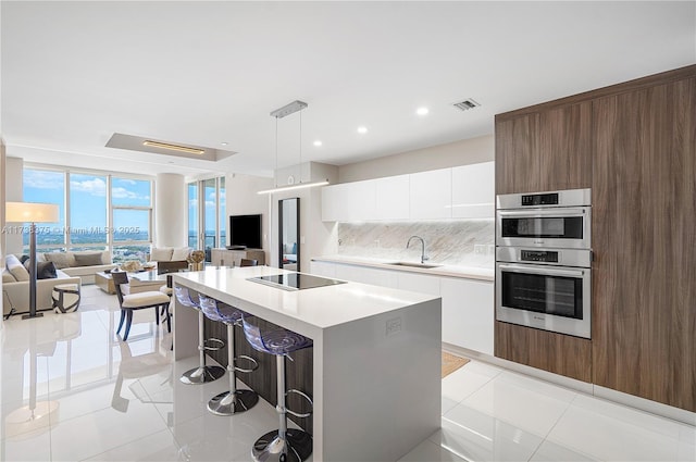 kitchen with visible vents, stainless steel double oven, a sink, modern cabinets, and black electric cooktop