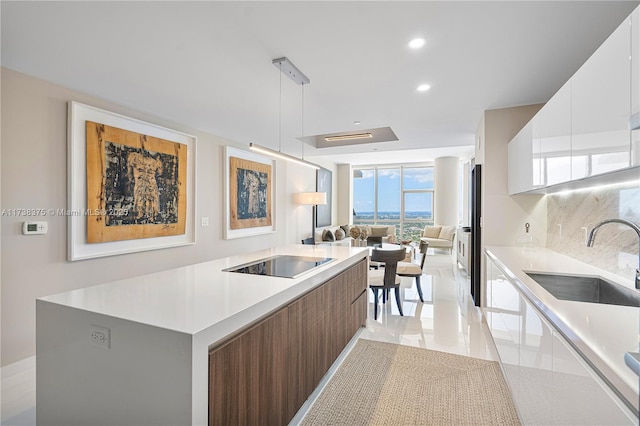 kitchen featuring a kitchen island, modern cabinets, black electric stovetop, and a sink