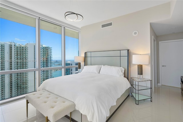 bedroom featuring floor to ceiling windows, visible vents, and a city view