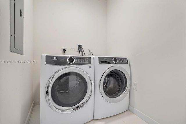 laundry room with laundry area, electric panel, baseboards, washing machine and dryer, and light tile patterned flooring