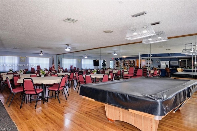 game room with hardwood / wood-style floors, pool table, and a textured ceiling