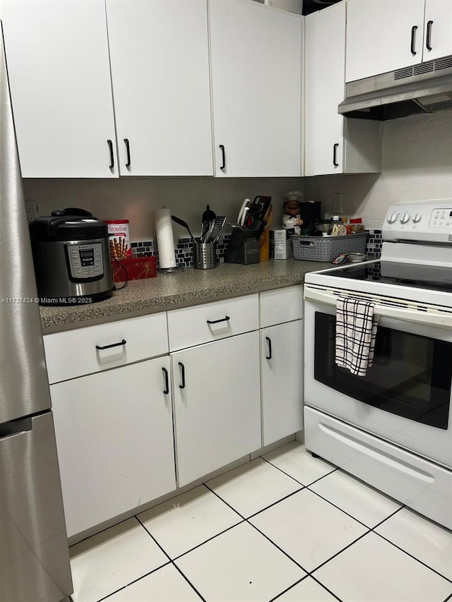 kitchen with white electric stove, light tile patterned floors, and white cabinets