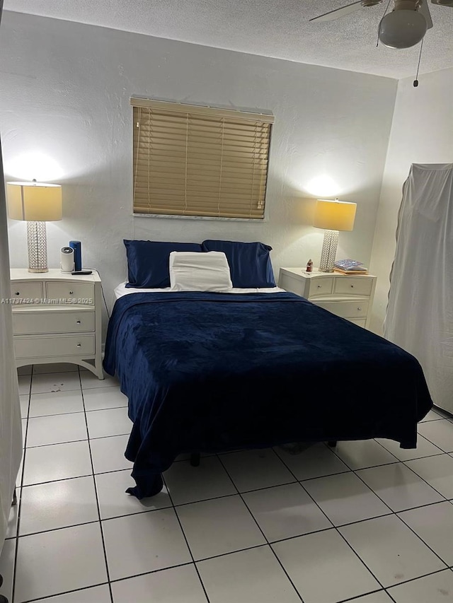 tiled bedroom with ceiling fan and a textured ceiling