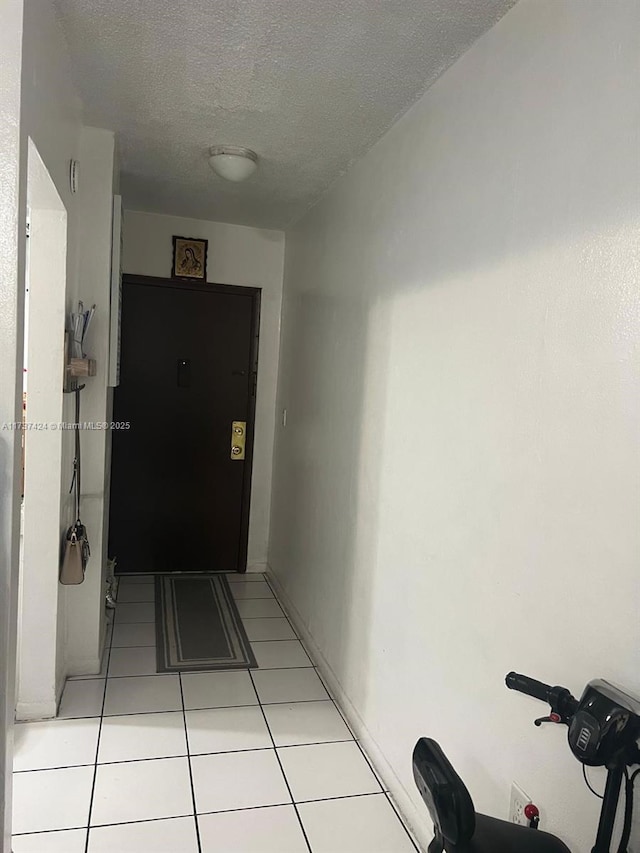 hall featuring light tile patterned flooring and a textured ceiling