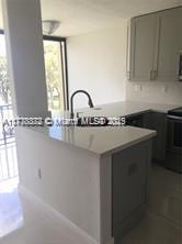 kitchen featuring range, gray cabinets, kitchen peninsula, and sink