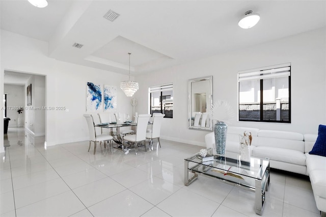 living room with a raised ceiling, light tile patterned floors, and a notable chandelier