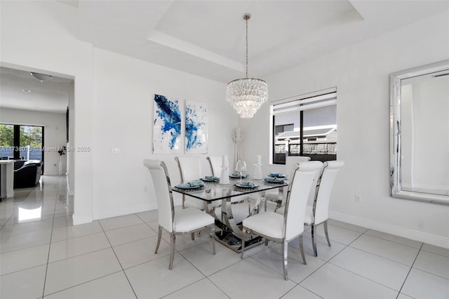 tiled dining area with an inviting chandelier and a tray ceiling