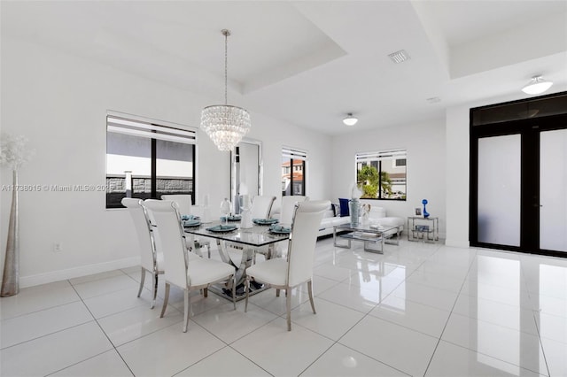 dining room with a notable chandelier, a tray ceiling, and light tile patterned floors