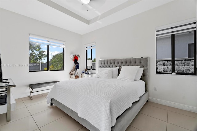 tiled bedroom featuring a raised ceiling and ceiling fan