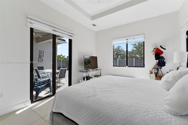 bedroom featuring multiple windows, light tile patterned flooring, access to exterior, and a tray ceiling