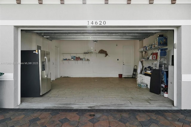 garage featuring stainless steel fridge with ice dispenser