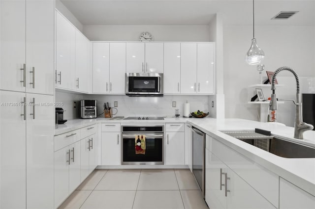 kitchen with sink, decorative light fixtures, appliances with stainless steel finishes, decorative backsplash, and white cabinets