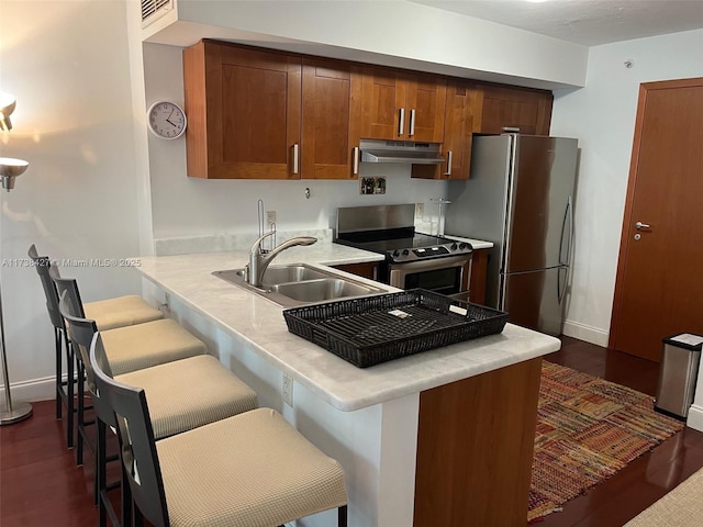 kitchen with stainless steel appliances, sink, a kitchen breakfast bar, and kitchen peninsula