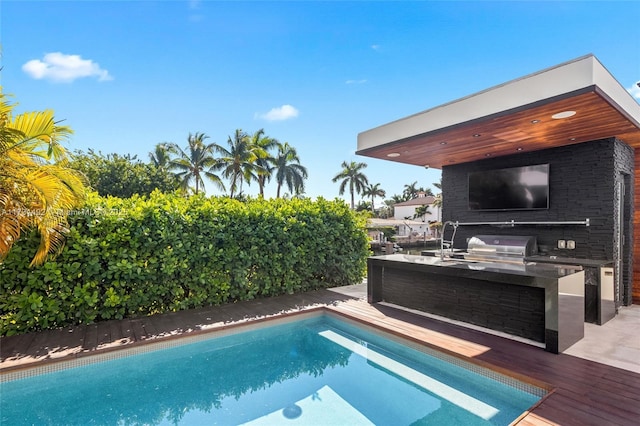 view of pool with a grill, sink, and exterior kitchen