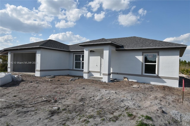 view of front of property featuring a garage, roof with shingles, and stucco siding