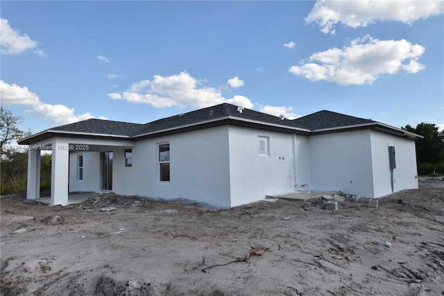 back of property featuring stucco siding and a shingled roof