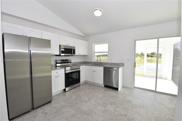 kitchen featuring lofted ceiling, sink, white cabinets, stainless steel appliances, and light stone countertops