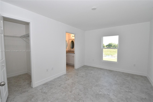 unfurnished bedroom featuring ensuite bathroom, a spacious closet, and a closet