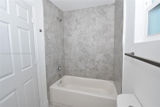 bathroom with toilet and tiled shower / bath combo