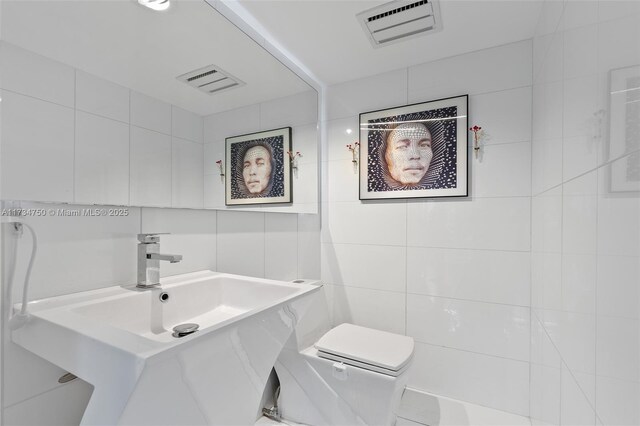 bathroom featuring tile walls and toilet