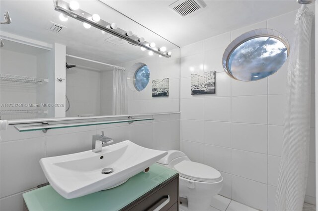 bathroom featuring vanity, toilet, a shower with shower curtain, and tile walls