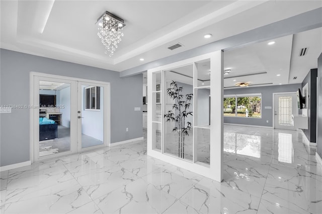 bathroom with french doors, a raised ceiling, and an inviting chandelier