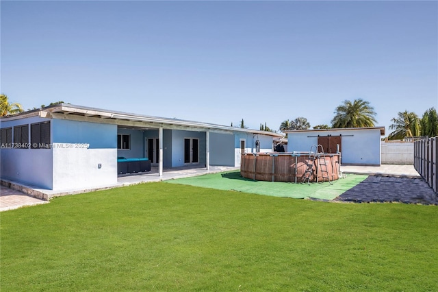 rear view of house featuring a pool, a lawn, and a patio