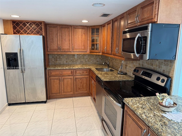 kitchen featuring stainless steel appliances, sink, light stone counters, and decorative backsplash