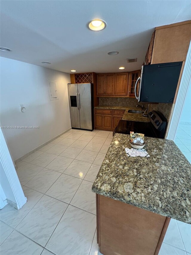 kitchen with stainless steel refrigerator with ice dispenser, sink, electric range, dark stone counters, and decorative backsplash