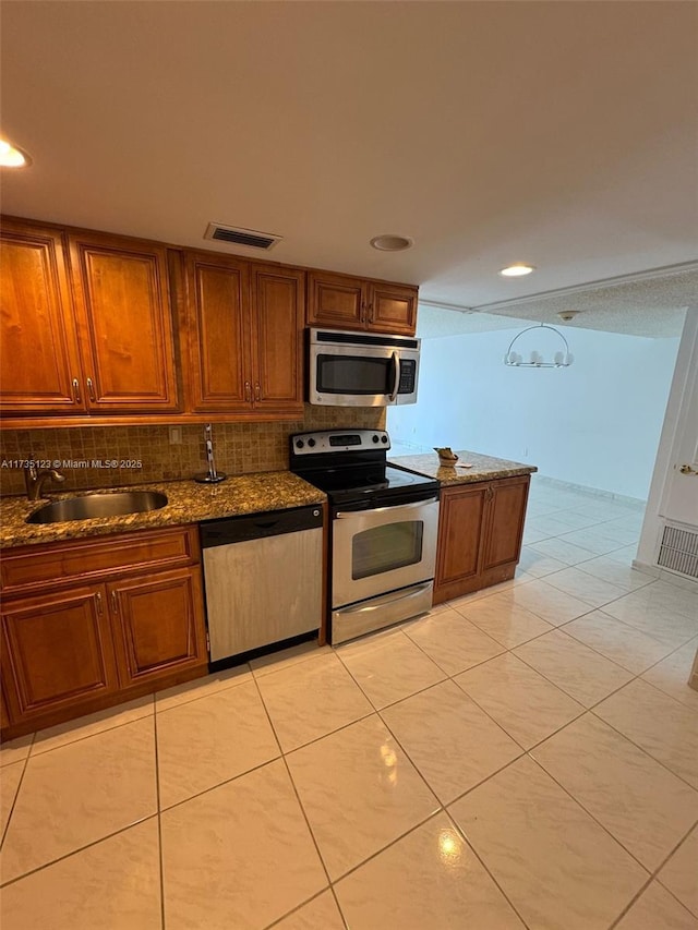 kitchen with sink, light tile patterned floors, appliances with stainless steel finishes, decorative backsplash, and dark stone counters