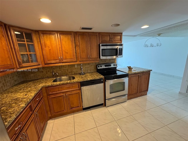 kitchen featuring stainless steel appliances, sink, stone counters, and backsplash