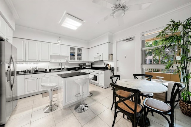 kitchen featuring light tile patterned floors, a center island, stainless steel refrigerator with ice dispenser, ornamental molding, and white cabinets