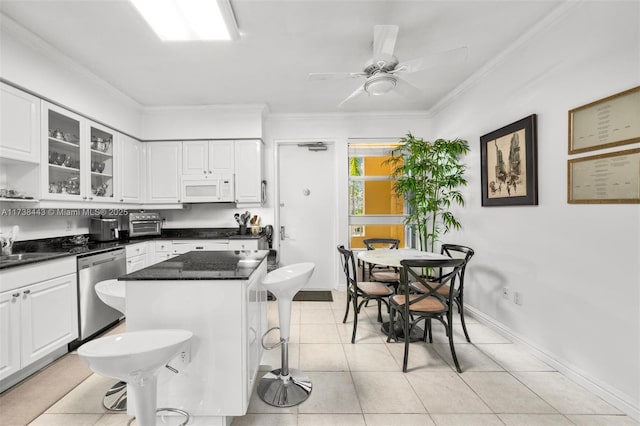 kitchen featuring white cabinetry, stainless steel dishwasher, a breakfast bar, and a kitchen island