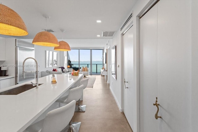 kitchen featuring hanging light fixtures, a water view, and sink