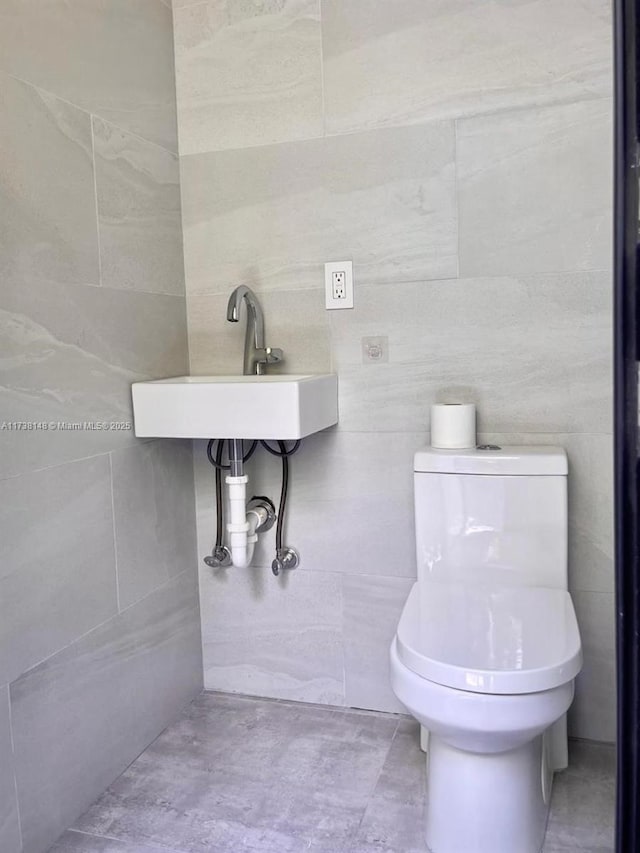 bathroom featuring toilet and tile walls