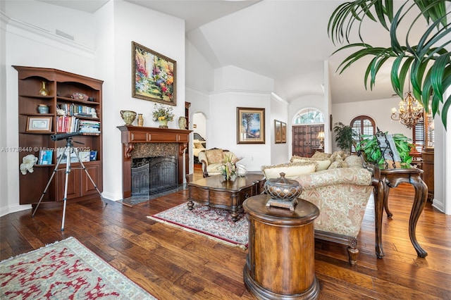 living room with vaulted ceiling, dark hardwood / wood-style floors, an inviting chandelier, and a high end fireplace