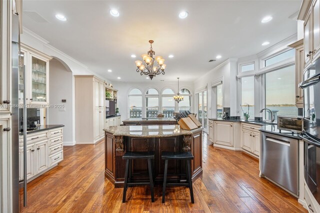 kitchen with a breakfast bar area, hanging light fixtures, stainless steel appliances, ornamental molding, and a kitchen island