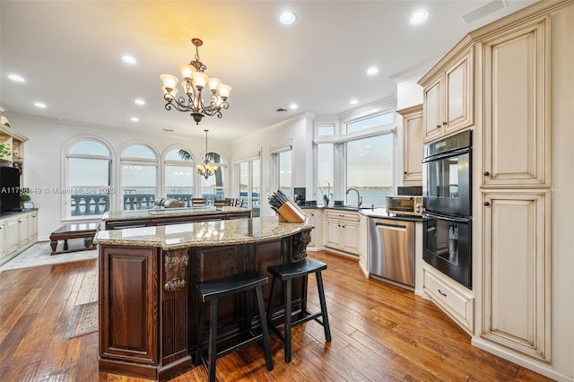 kitchen featuring hanging light fixtures, a chandelier, dishwasher, and a kitchen bar