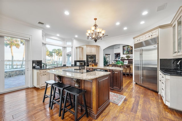 kitchen featuring a kitchen bar, decorative light fixtures, a center island, dark stone countertops, and black appliances