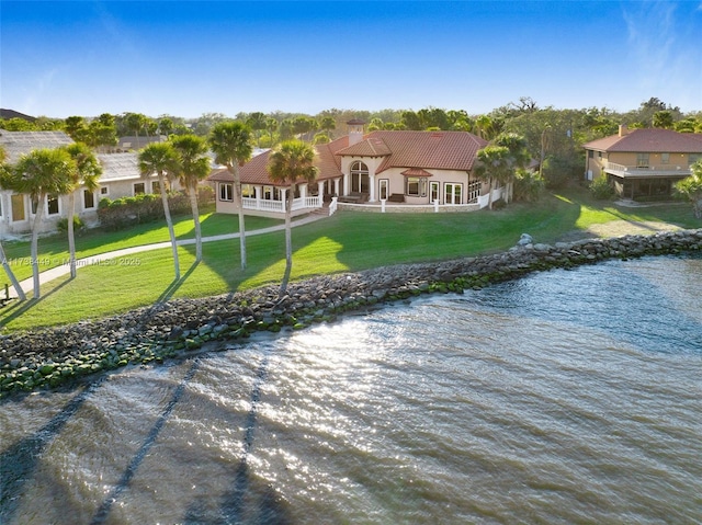back of house with a water view and a lawn